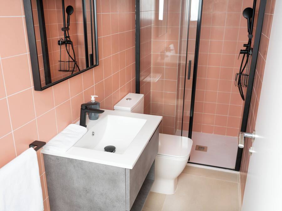 A modern bathroom with a large white sink, a toilet, and a glass shower enclosure.