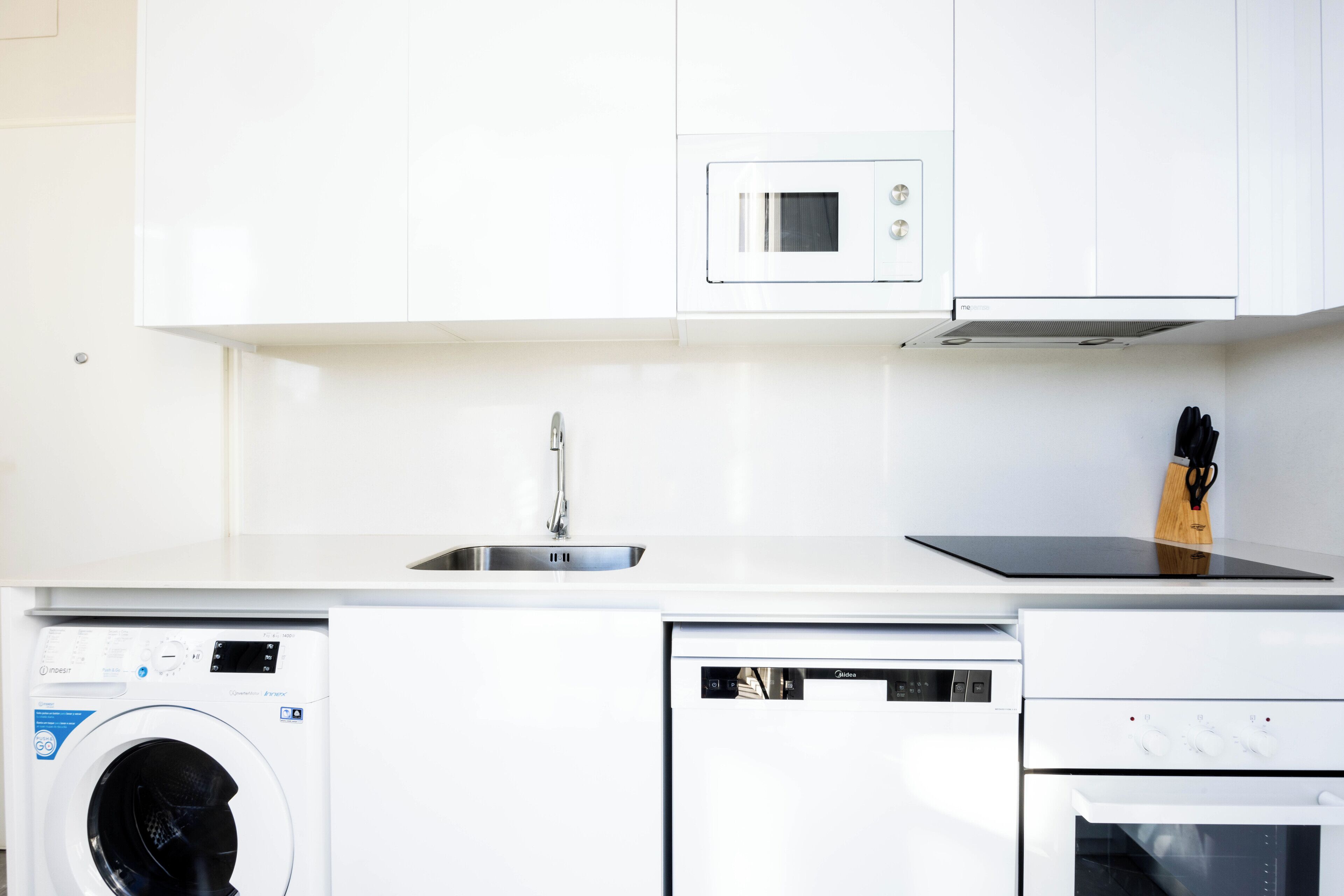 A modern kitchen with a built-in washing machine, dishwasher, microwave, and oven.