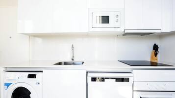 A modern kitchen with a built-in washing machine, dishwasher, microwave, and oven.