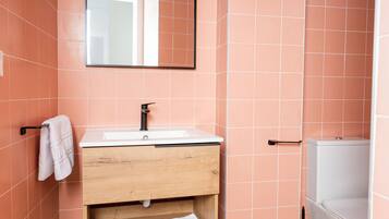 A bathroom with a white sink, wooden vanity, and a white toilet.