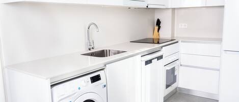 Une cuisine moderne équipée d’un lave-linge, d’un lave-vaisselle et d’un four intégrés.