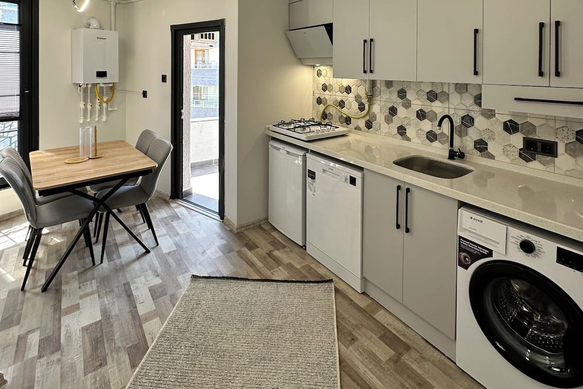 Una cocina moderna con armarios blancos, estufa integrada, lavavajillas y lavadora.