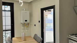 A modern kitchen with a gas stove, a white refrigerator, and a dining area with a wooden table and chairs. - ÖZTÜRK VIP (Trabzon)
