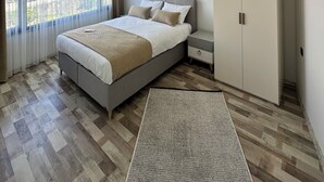 A modern bedroom with a large bed, a wardrobe, and a view of the outside. - ÖZTÜRK VIP (Trabzon)