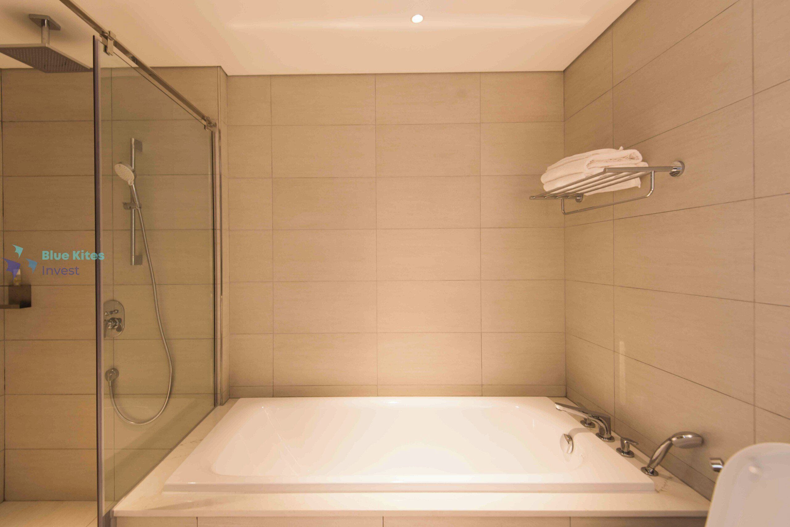 A modern bathroom with a glass-enclosed shower, a large bathtub, and a towel rack on the wall.