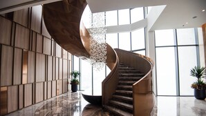Eine Wendeltreppe mit Holzvertäfelung, umgeben von einem polierten Marmorboden und großen Fenstern.