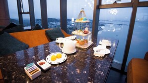 Ein Esstisch mit Blick auf die Stadt, ein mehrstufiger Dessertteller und eine Kaffeestation.