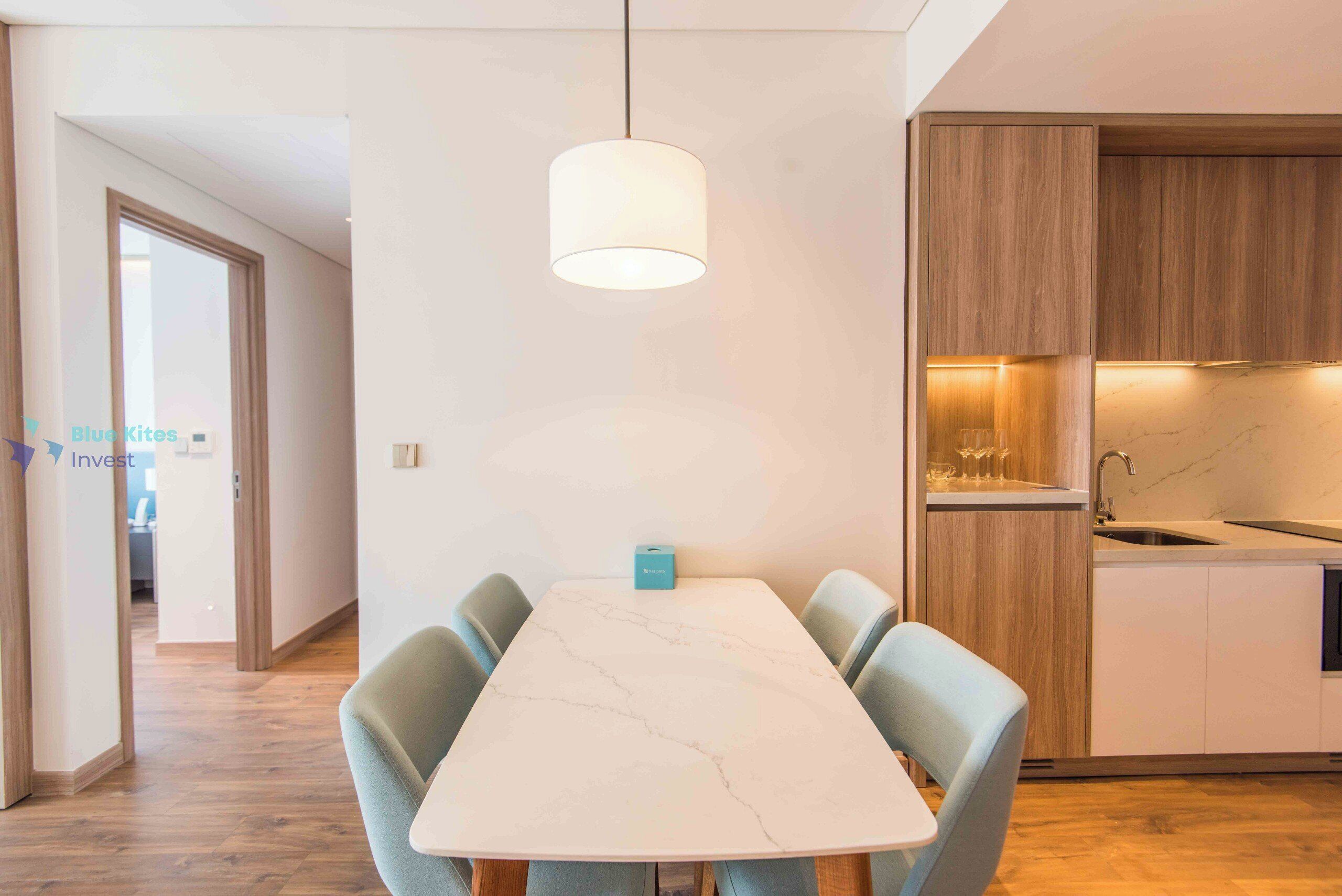 A modern kitchen with wooden cabinets, a marble countertop, and a hanging pendant light.