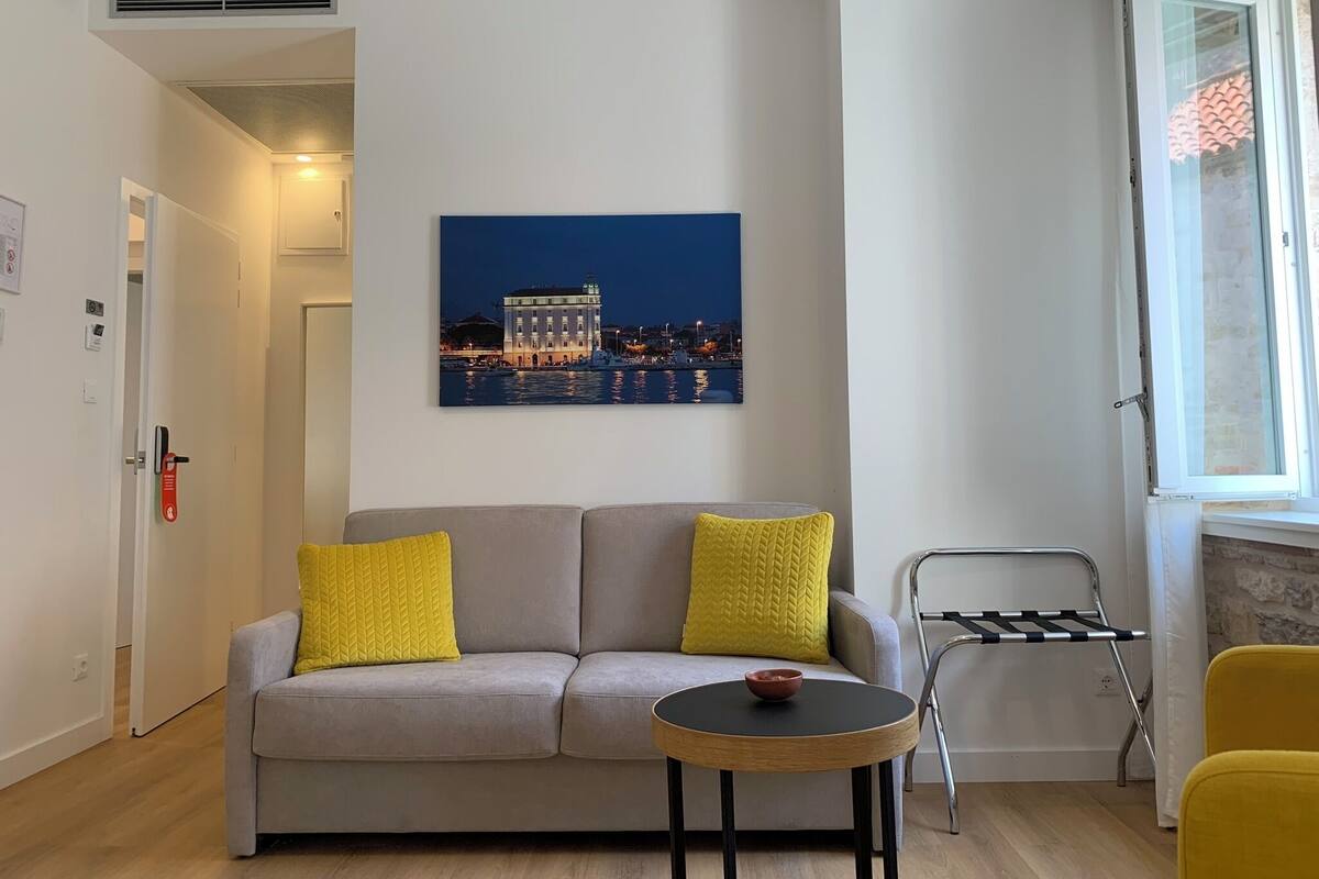 Ein modernes Wohnzimmer mit einer Couch, einem kleinen runden Tisch und einem Stadtbild.