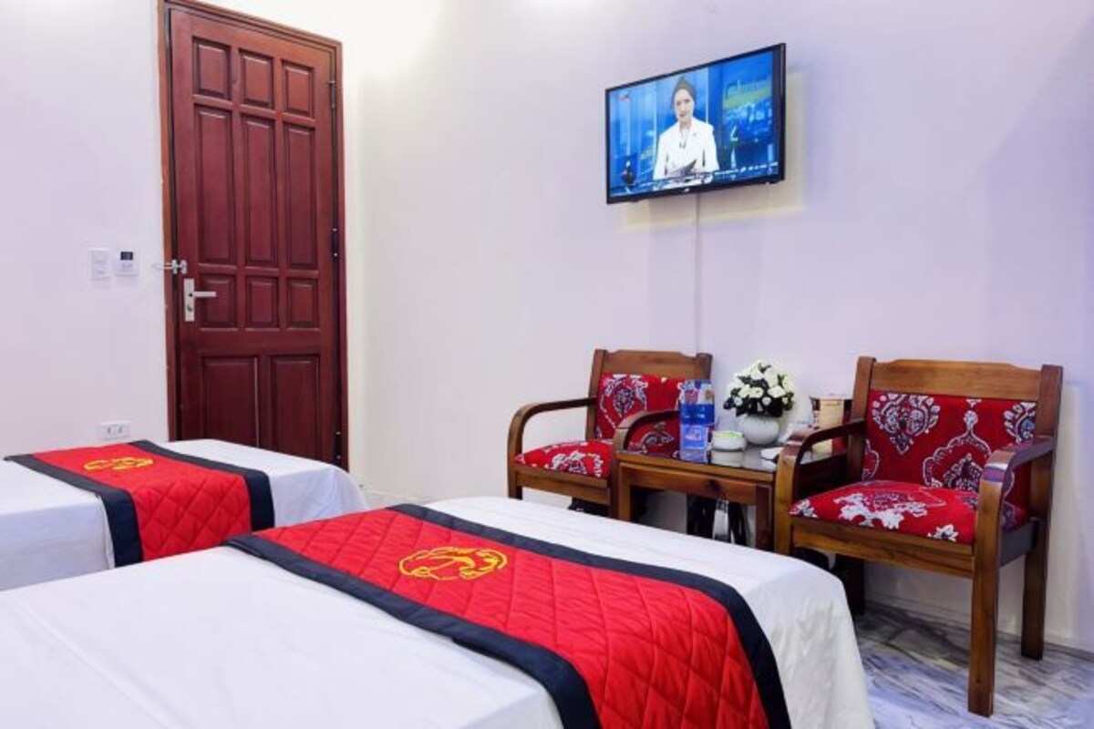 Habitación de hotel con dos camas, televisión, puerta de madera y una mesa con sillas.