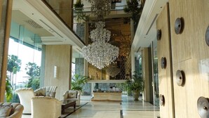 Eine geräumige Lobby mit hoher Decke, einem großen Kronleuchter und einem Empfangstresen.