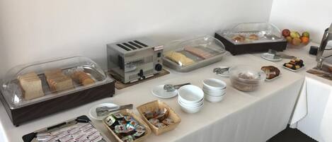 A buffet table with various food items and condiments.