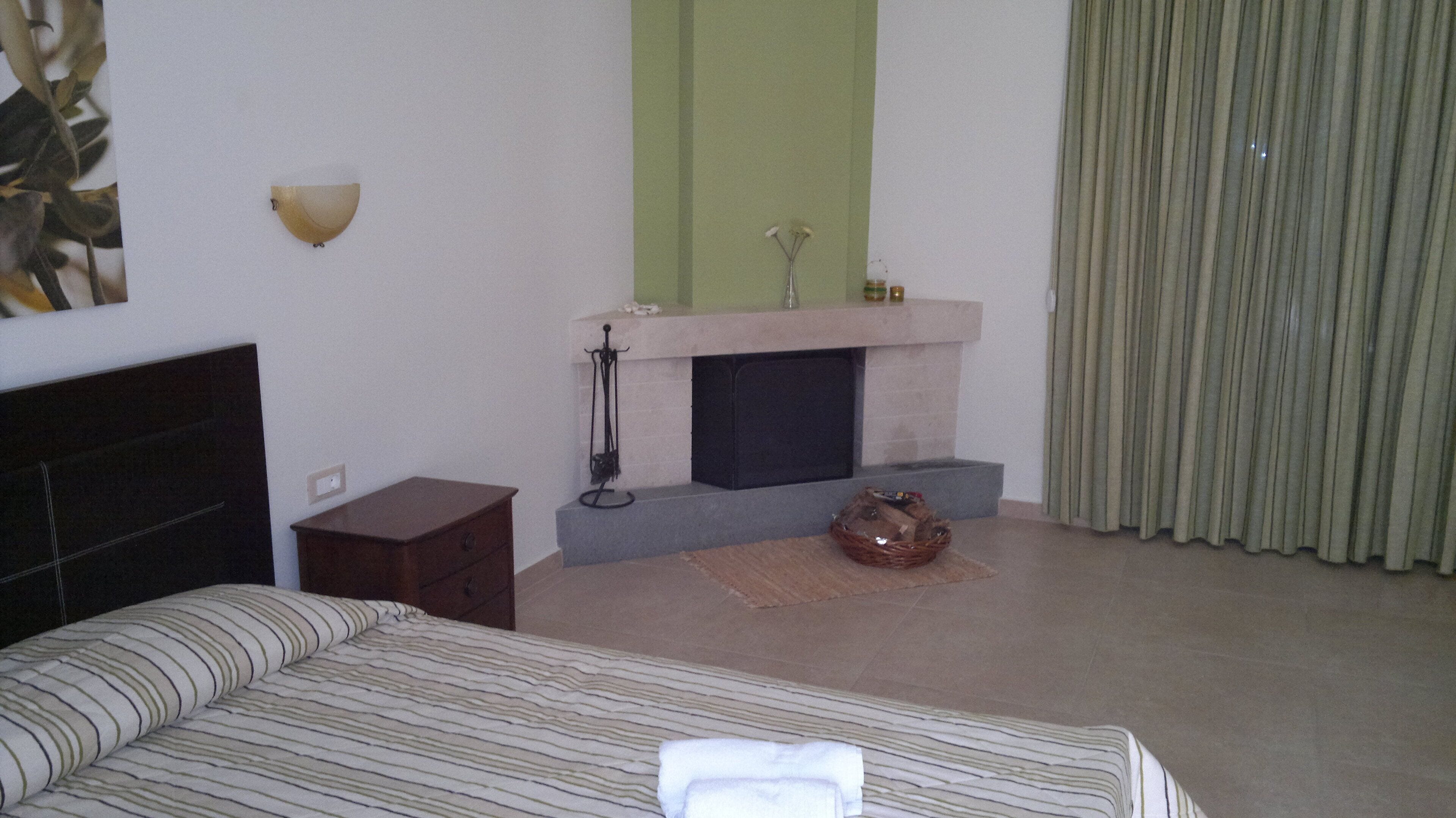 A bedroom with a bed, a dresser, a fireplace, and a curtain.