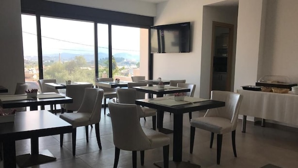 Un comedor con varias mesas y sillas, un televisor de pantalla plana montado en la pared y un mostrador de buffet a la derecha.
