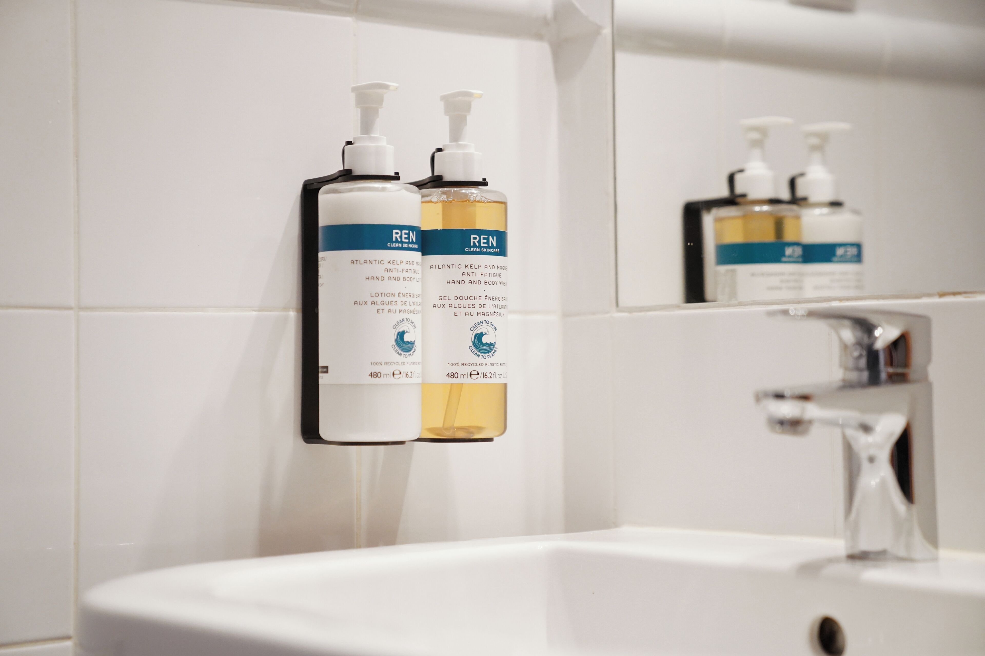 A bathroom with two bottles of REN body wash and a sink.