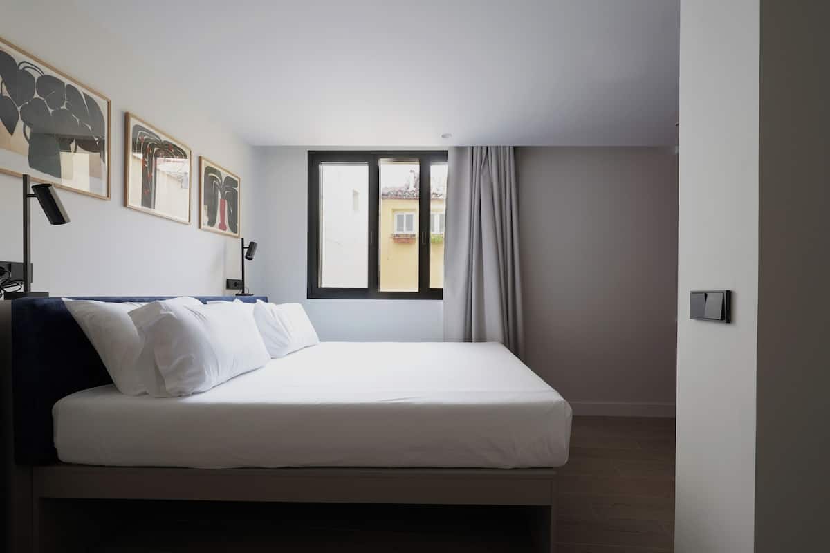 Un dormitorio moderno con una cama grande, una ventana con cortinas y cuadros en la pared.