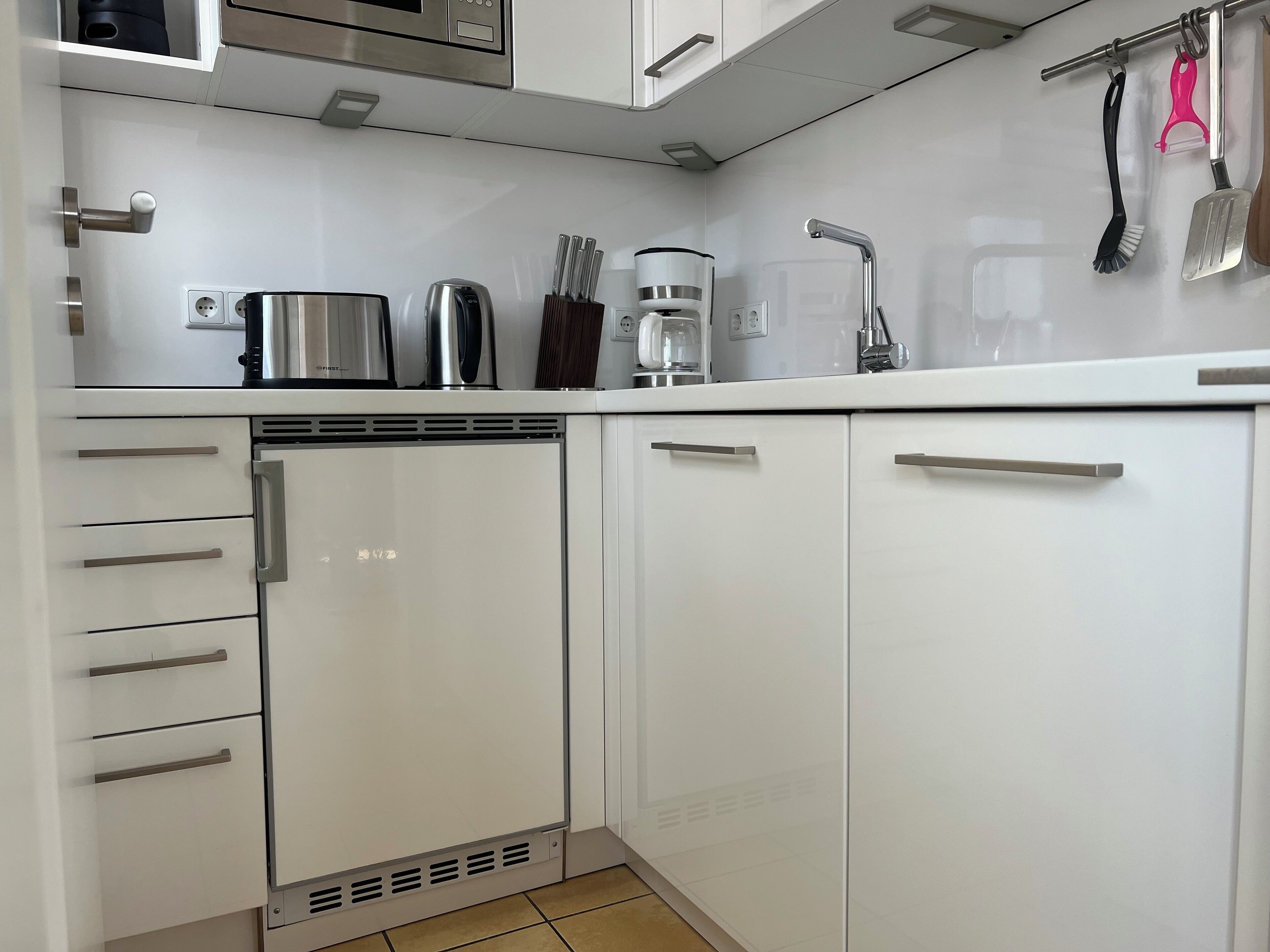 A modern kitchen with white cabinets, stainless steel appliances, and a tiled backsplash.