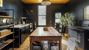 Una cocina moderna con una mesa de madera, electrodomésticos negros y un ventanal grande.