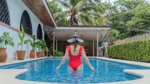 A woman in a red swimsuit standing in a pool with a house in the background. - 5 min to Beach ~ Private Pool ~ European style! (Sardinal)
