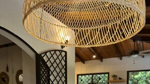 A dining area with a long wooden table, potted plants, and a woven ceiling light fixture. - 5 min to Beach ~ Private Pool ~ European style! (Sardinal)