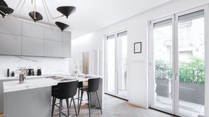 A modern kitchen with a central island, black bar stools, and pendant lighting.