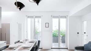 A modern kitchen with white cabinets, a dining table set for four, and a large window with a view of greenery outside.