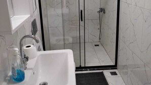 A bathroom with a glass-enclosed shower, a white sink, and a mirror above it. - GARDEN Prizma Pansiyon & Aparts (Kemer)