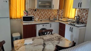 A compact kitchen with a microwave, sink, stove, and a washing machine. - GARDEN Prizma Pansiyon & Aparts (Kemer)