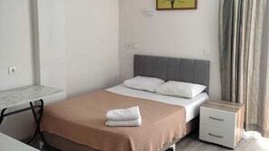 A modern bedroom with a bed, bedside tables, a desk, and a painting on the wall. - GARDEN Prizma Pansiyon & Aparts (Kemer)