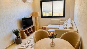 A living room with a TV, sofa, chairs, and a table with a vase. - 2 Bedroom Apartment in Marrakech (Marrakech)
