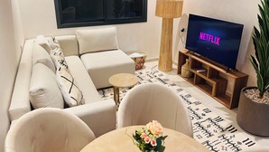 A modern living room with a sofa, a coffee table, a TV displaying 'NETFLIX', and a potted plant. - 2 Bedroom Apartment in Marrakech (Marrakech)
