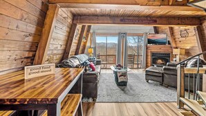 L’intérieur chaleureux d’un chalet, avec un décor en bois, une cheminée, un canapé et une table à manger.