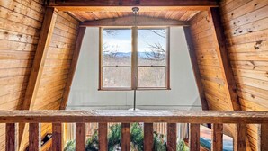 Une pièce mansardée en bois, dotée d’une grande fenêtre et offrant une vue sur les montagnes.