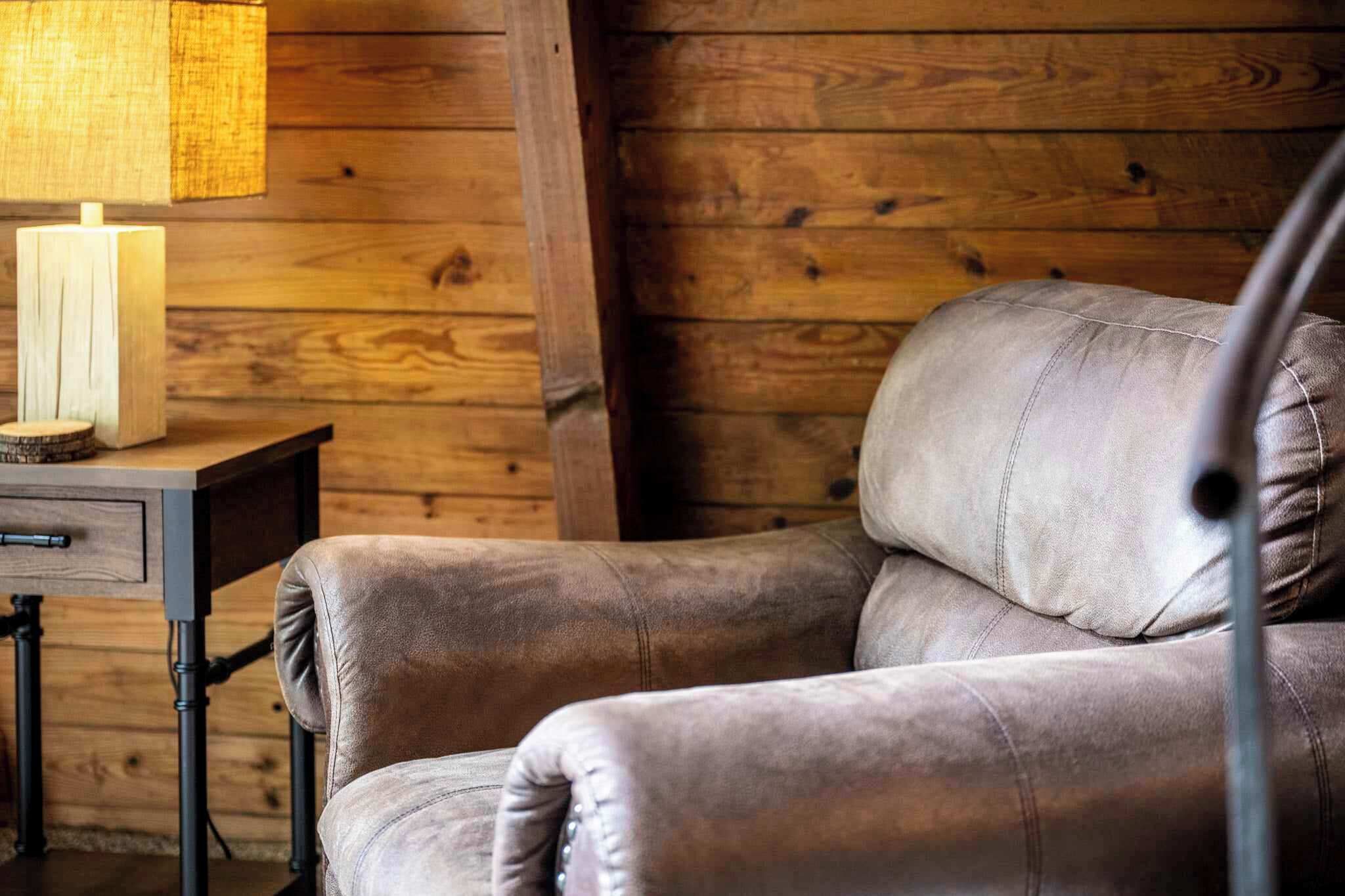Een leren fauteuil in een houten kamer in chaletstijl, met een tafel en kaarsen.