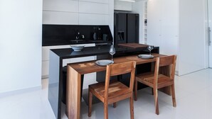 A modern kitchen with a black countertop, white cabinets, and a wooden dining table with four chairs. - Marousi 2 Bd Luxury Living w Shared Pool (Marousi)