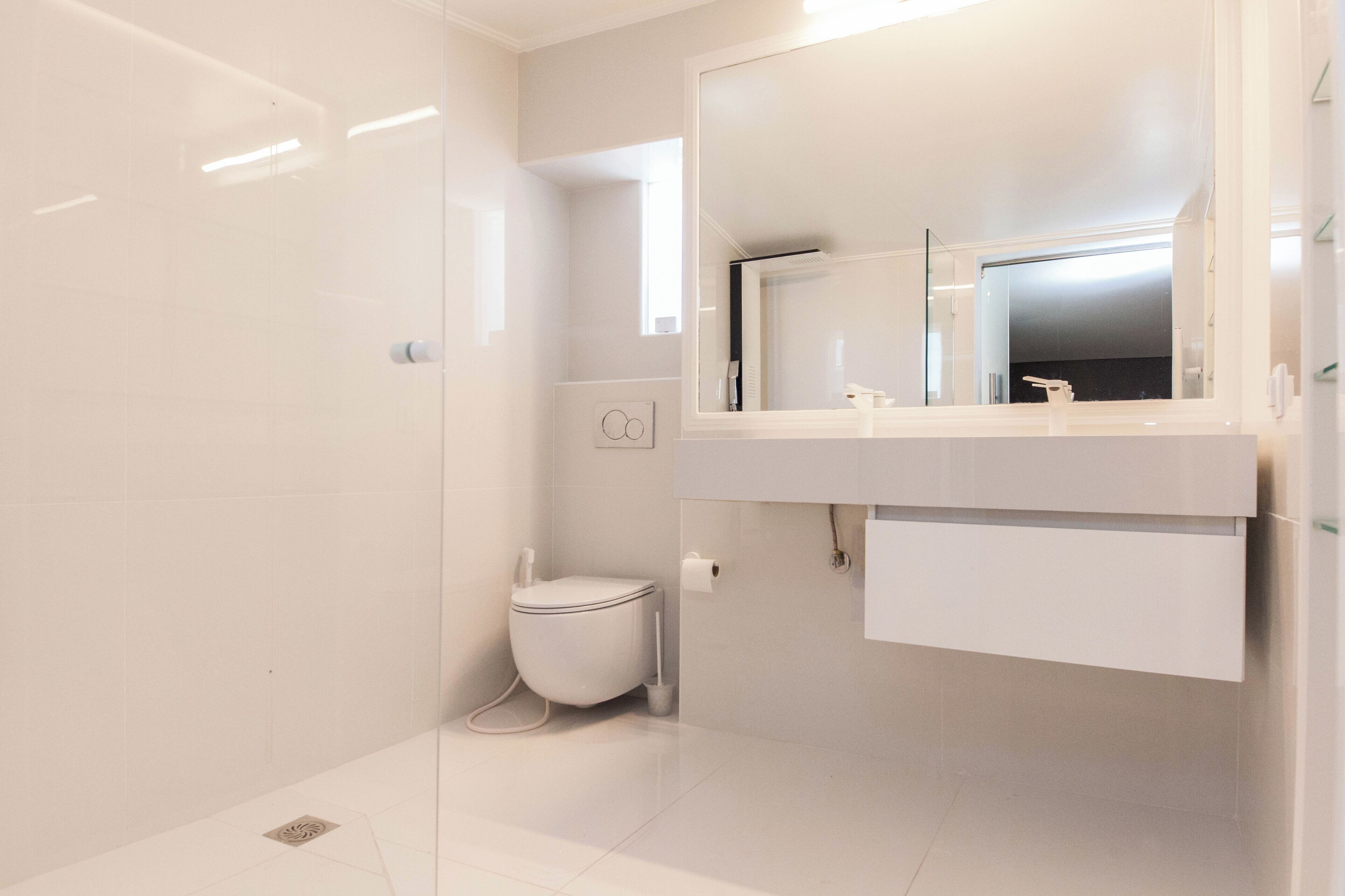 Une salle de bain moderne dotée d’une douche à parois de verre, de toilettes et d’un meuble-lavabo avec un miroir et un évier.
