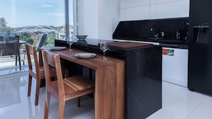 A modern kitchen with a wooden dining table, chairs, and a black countertop. - Marousi 2 Bd Luxury Living w Shared Pool (Marousi)