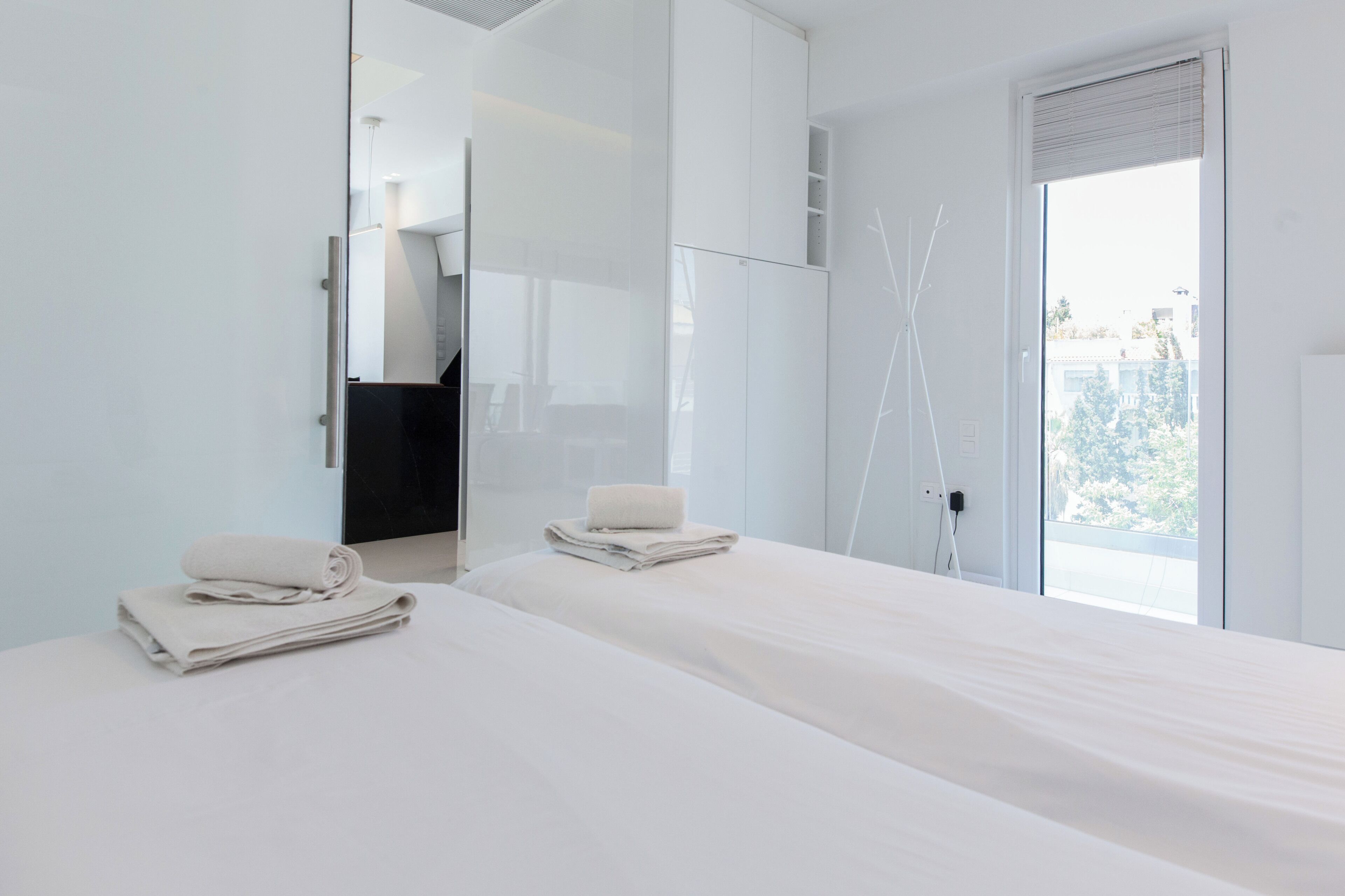A modern hotel room with a large bed, a walk-in closet, and a view of the outdoors.