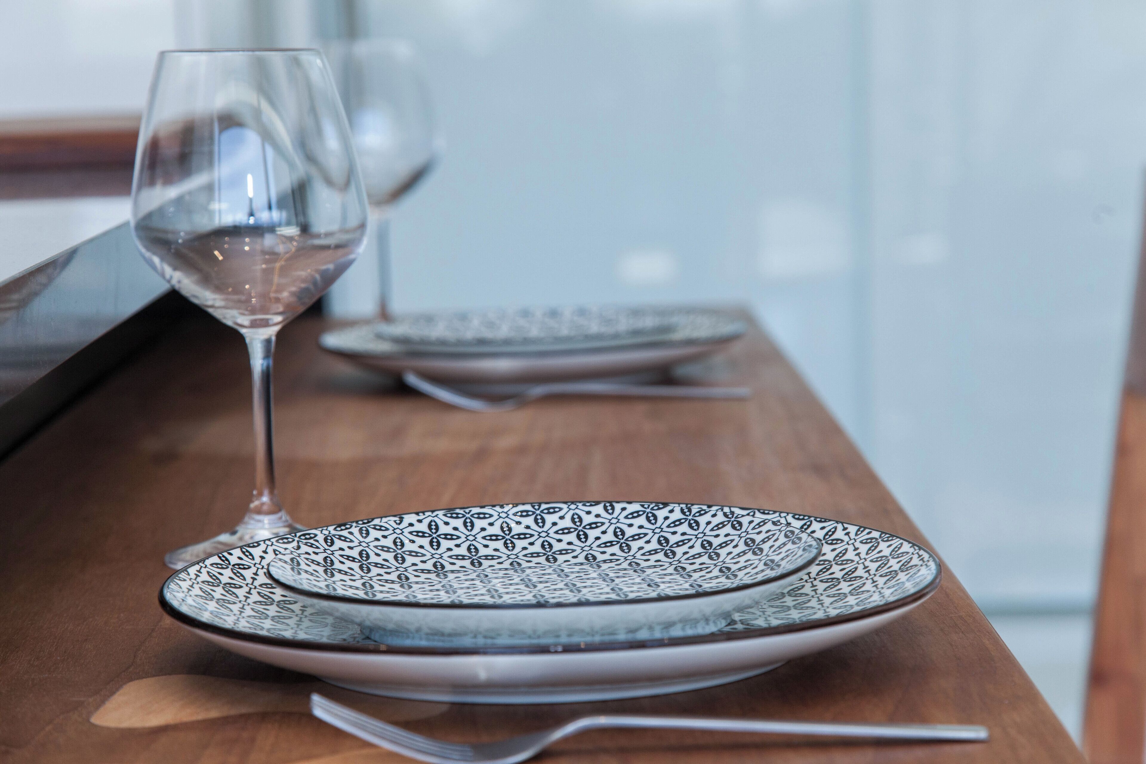Un tavolo da pranzo con un bicchiere di vino di cristallo e piatti decorati.