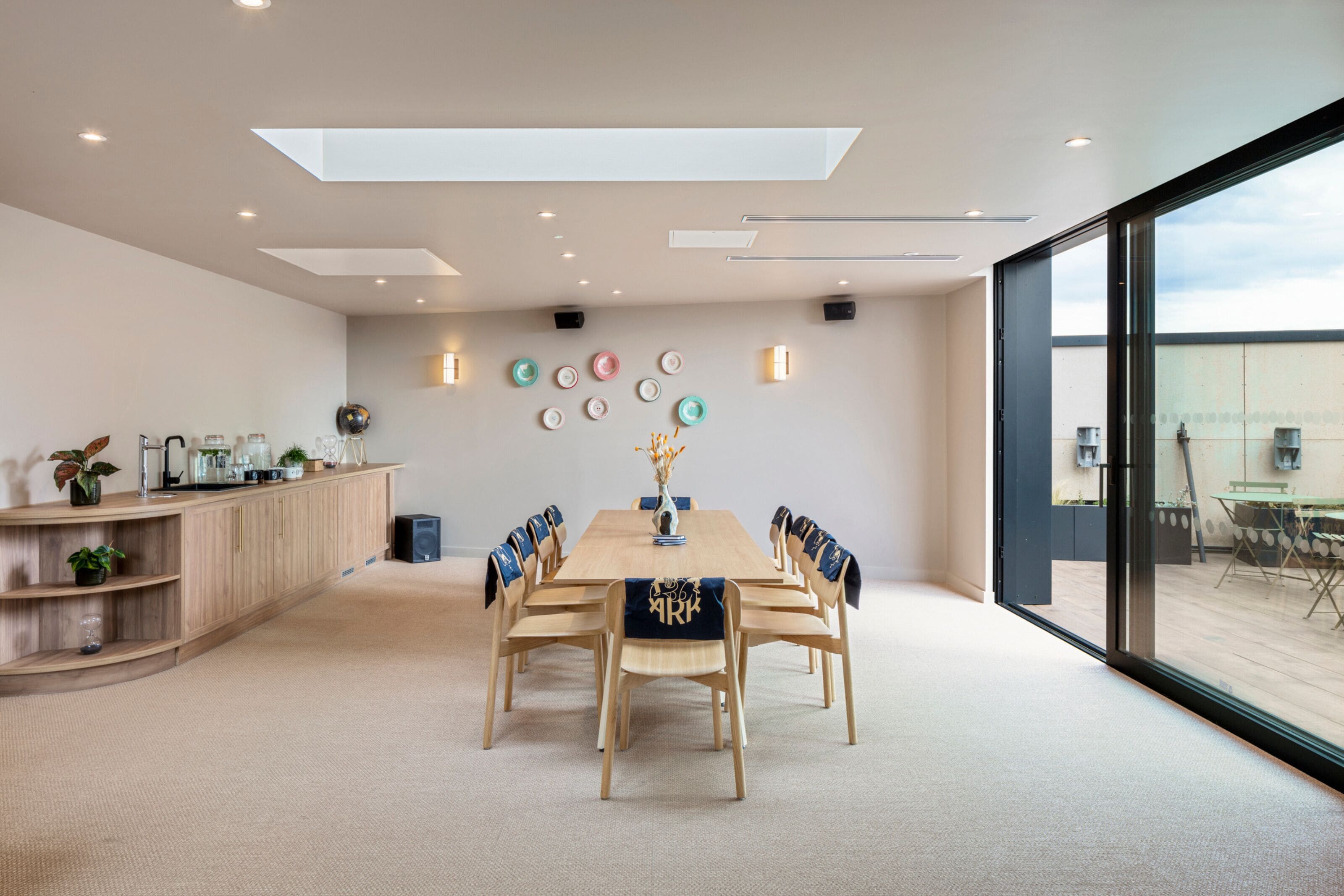 A modern meeting room with a wooden table, chairs, and a decorative wall.