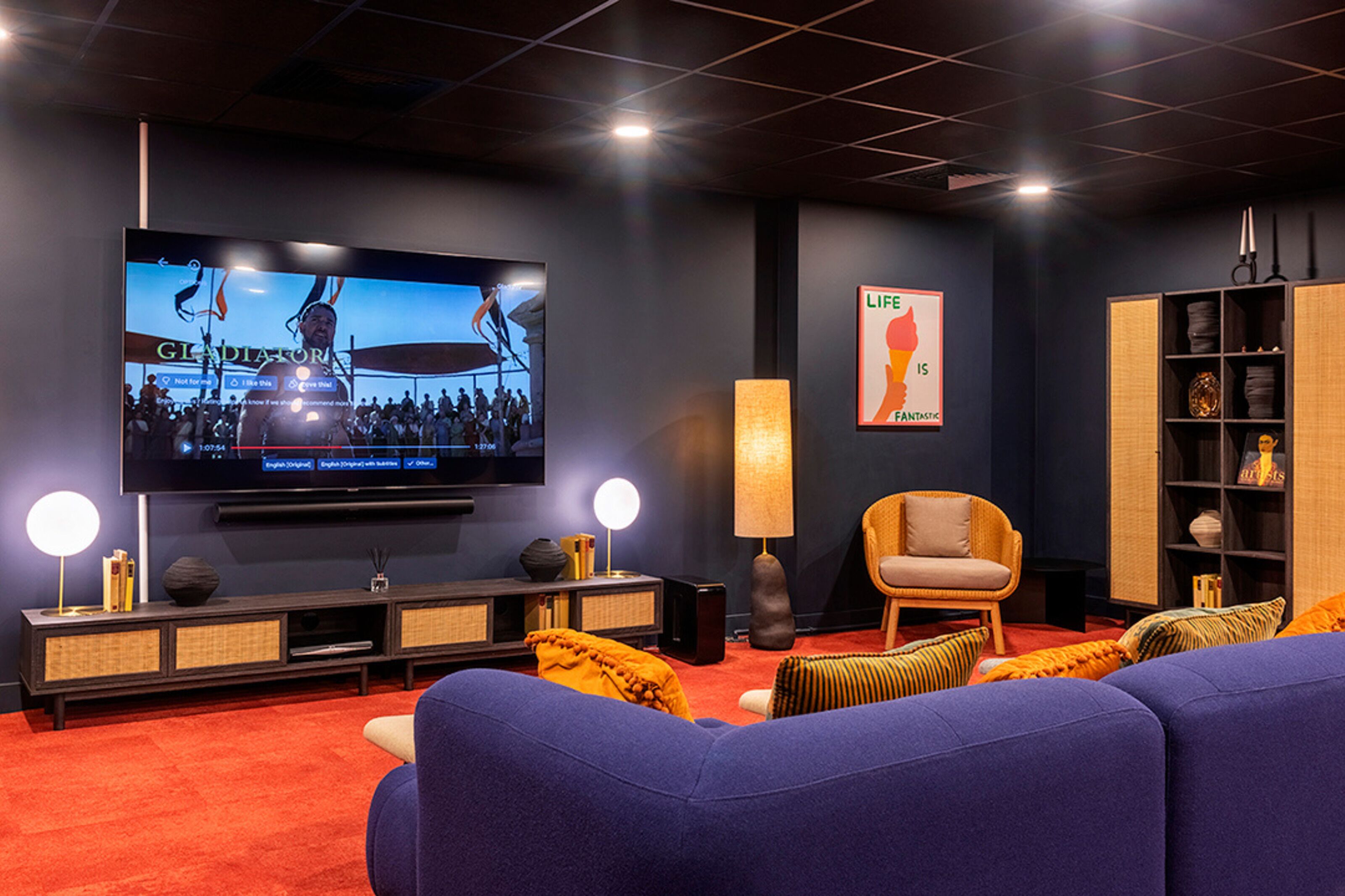 Uma sala de estar moderna com uma televisão de tela grande, assentos confortáveis e uma estante de livros.