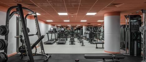 A gym with various exercise equipment, including weight machines, benches, and dumbbells.