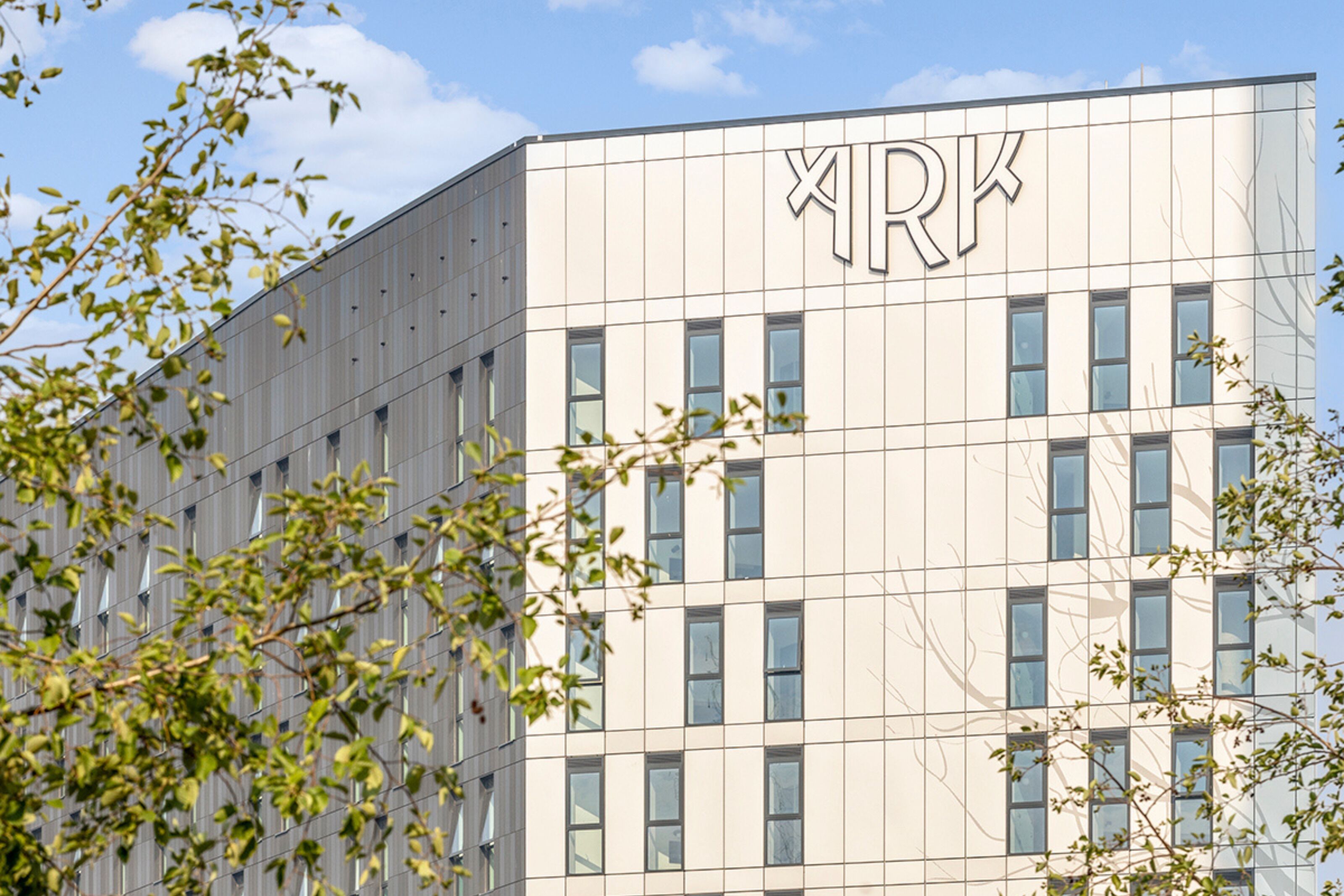 A modern building with a grid of windows and a large 'RK' sign on the facade.