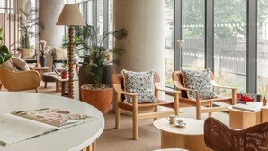 Un espace de détente moderne, doté de sièges confortables, de grandes fenêtres et de plantes d’intérieur.