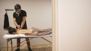 A massage therapy session in a room with a wooden floor and a simple, uncluttered layout. - Rebalance Apartments (Athens)