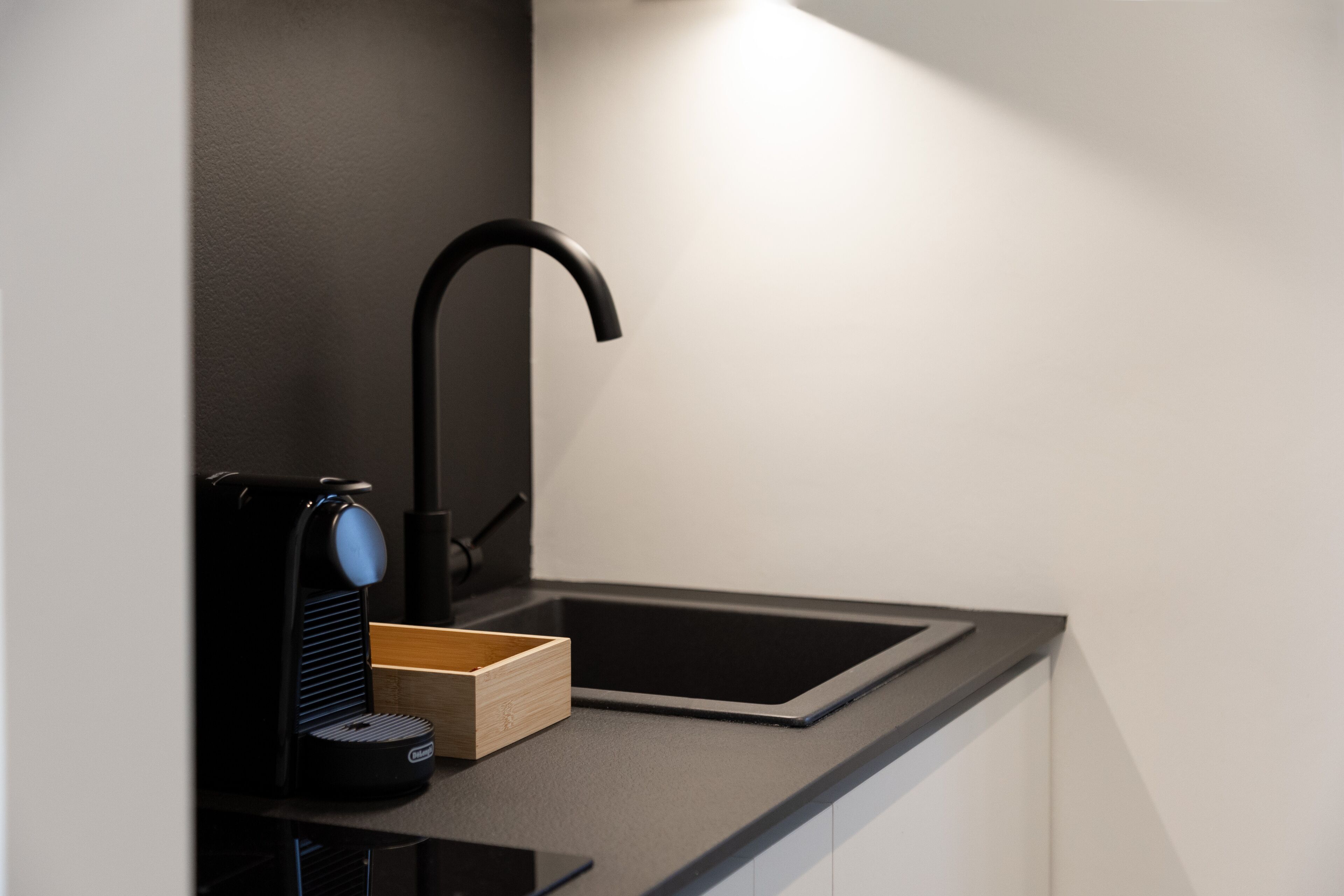 Una cocina moderna con encimera negra, pileta integrada y cafetera.