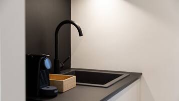 Una cocina moderna con encimera negra, pileta integrada y cafetera.