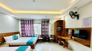 A hotel room with two beds, a TV, a desk, and a chair.