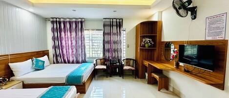 A hotel room with two beds, a TV, a desk, and a chair.