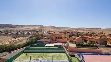 A residential area with houses, a tennis court, and a desert landscape in the background.